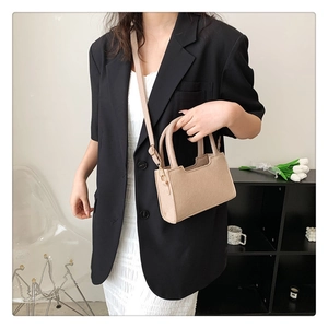 Detailed view of oatmeal felt crossbody square bag worn with a stylish blazer