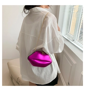 Détail du sac à bandoulière en forme de lèvres magenta métallisé avec chaîne dorée