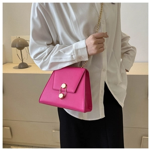 Détail du sac bandoulière rose vif avec boucle hexagonale dorée et bandoulière en chaîne