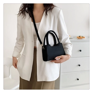 Minimalist black felt crossbody bag styled with a white blazer and olive green skirt