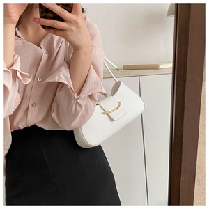 Minimalist white leather underarm bag with gold metal buckle shown in a mirror selfie style