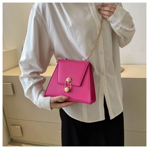 Détail du sac bandoulière rouge rose avec boucle dorée et bandoulière chaîne élégante