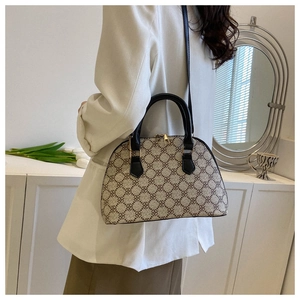 Detail of a chic beige shell handbag with clover pattern and gold zipper on a white cabinet