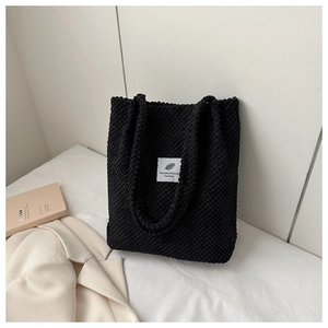 Bolso tote minimalista de pana negra con etiqueta blanca en un ambiente acogedor