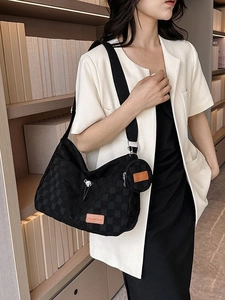 Fashionable black checkerboard tote bag with round coin purse worn by model in a library