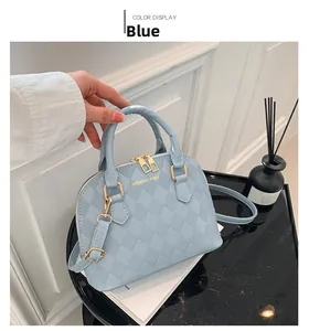 Close-up of light blue shell bag with diamond quilt pattern and golden zippers