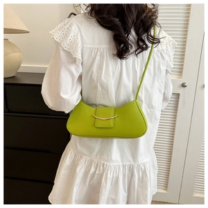 Close-up of bright green leather crescent bag with gold buckle and ruffled white top