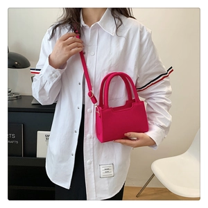 Fuchsia fetted mini square bag shown as a crossbody on a model with white shirt
