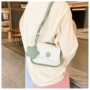 Detail of crossbody bag with white and green contrast colors and flower charm