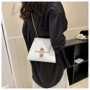 Sac à rabat trapèze blanc avec chaîne dorée porté par un mannequin pour un style minimaliste