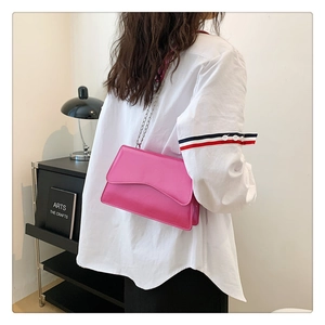 Detail of rose pink patent leather crossbody bag with wave flap and silver chain strap
