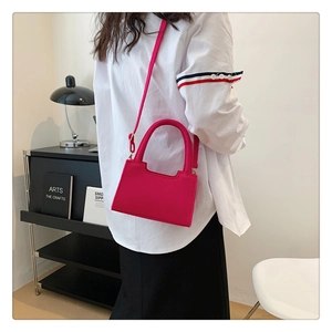 Detail of fuchsia felt handbag with minimalist trapezoidal design and slim shoulder strap