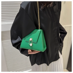 Détail du sac vert citron à chaîne dorée avec fermoir à gemmes blanches sur un mannequin