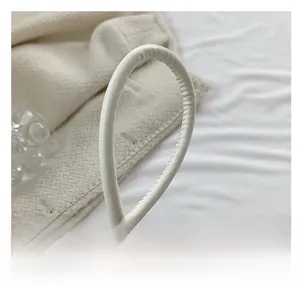 Close-up of white PU leather bag handle showing detailed manual stitching craftsmanship