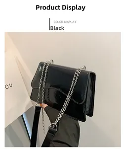 Detail of glossy black leather crossbody bag with silver chain strap and flap closure