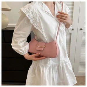 Detail of light pink crescent underarm bag with gold metal buckle on white lace dress