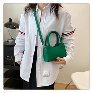 Detail of bright green felt handbag with gold hardware styled on a model in a room