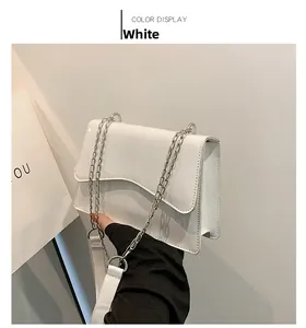 Detail of white patent leather shoulder bag with wavy flap and silver chain strap