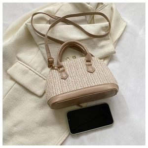 Détail du sac coquillage tissé avec poignées en cuir et bandoulière réglable