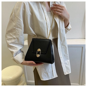 Sac à bandoulière trapèze noir chic avec fermoir doré porté par un mannequin en tenue décontractée