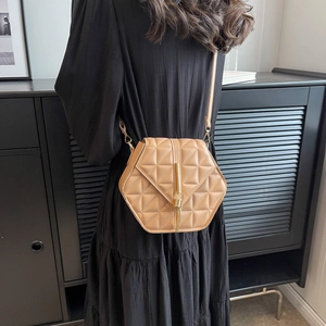Beige hexagonal crossbody bag with quilted leather texture and gold tassel details