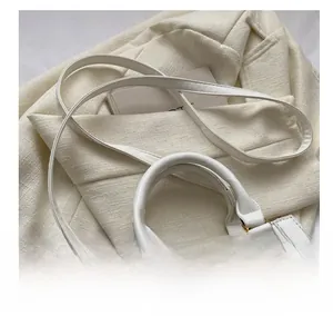 Close-up detail of white faux crocodile embossed leather handbag with metal hardware
