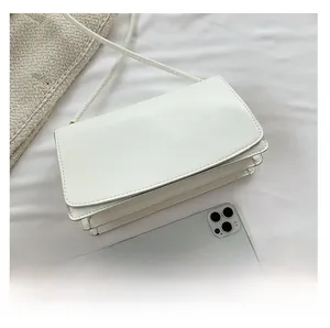 Detailed view of white minimalist rectangular handbag with phone for size comparison