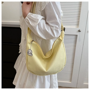 Detailed texture of light yellow canvas crossbody bag with cute white sheep pendant