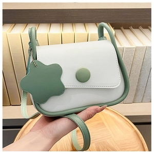 Detail of a green and white small square bag with floral pendant and round buckle strap