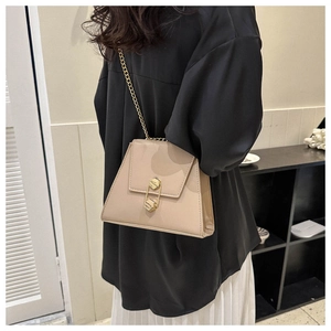 Détail du sac bandoulière trapèze beige avec chaîne dorée et fermoir hexagonal chic