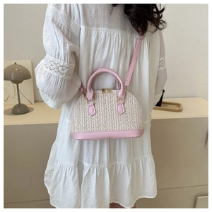 Détail du sac coquillage tissé rose et beige avec ferrures dorées et base en cuir souple