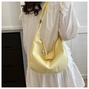 Detail of light yellow canvas tote bag with wide strap and white puppy charm