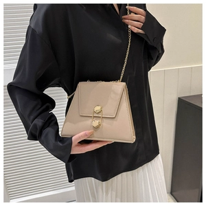 Sac trapèze beige chic à chaîne dorée et fermoir hexagonal porté avec tenue minimaliste