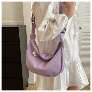 Light purple corduroy crescent bag with adjustable strap and cute dog charm shown on model