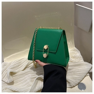 Détail d'un sac à chaîne vert en cuir avec une boucle hexagonale en métal et chaîne dorée