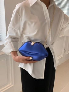 Sac à bandoulière bleu métallique en forme de lèvres avec chaîne dorée porté par un mannequin