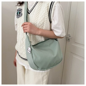 Detail of light green corduroy half-moon crossbody bag with cute dog pendant accessory