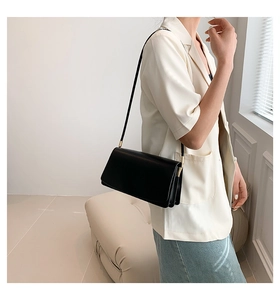 Minimalist black leather underarm bag featuring elegant gold hardware details on shoulder strap