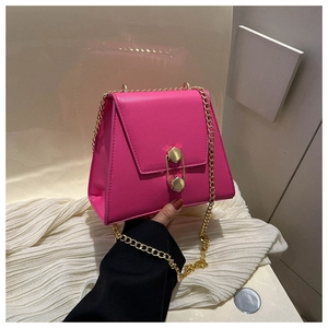 Détail du sac trapèze rouge rose avec fermoir hexagonal doré et bandoulière chaîne