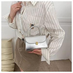 Detail showing metallic silver square bag with gold buckle and adjustable strap