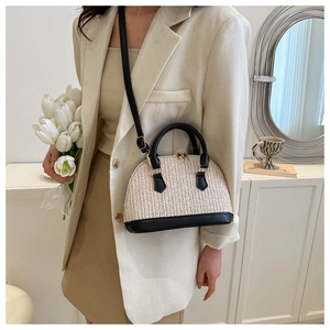 Gros plan du sac en paille beige avec poignée en cuir noir et détails dorés élégants