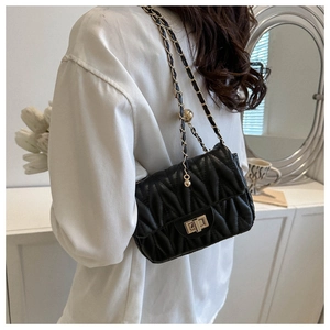 Quilted black crossbody bag with gold chain strap shown in a lifestyle indoor setting