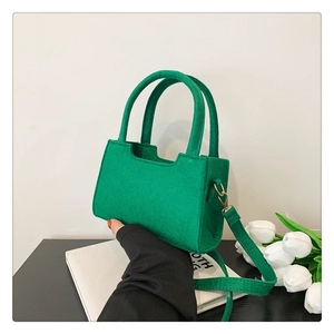 Detail of green felt mini tote bag showing dual handles and golden metal buckle