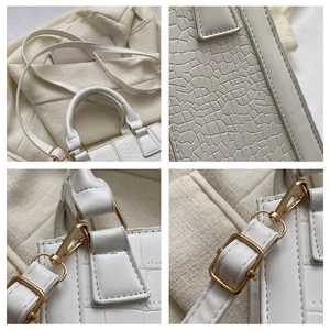 Detail of white crocodile pattern handbag showing golden metal hardware and textures