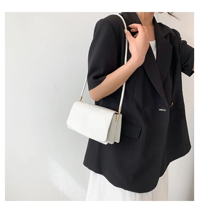 Close-up of a minimalist white rectangular shoulder bag with golden metallic hardware