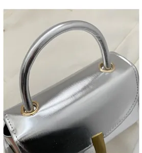 Detail of silver metallic handbag showing the smooth finish and gold eyelet hardware