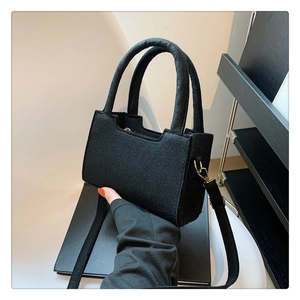Detailed macro view of black felt handbag with elegant golden metal hardware and strap hooks