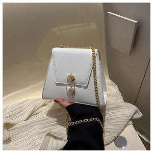 Détail d'un sac à main blanc avec fermoir hexagonal doré et bandoulière en chaîne