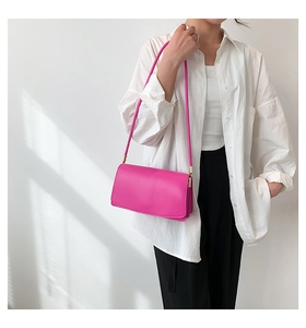 Detailed view of magenta rectangular underarm bag with glossy finish and gold hardware