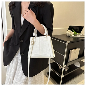 Detail of white crocodile embossed tote bag with gold hardware held by a model